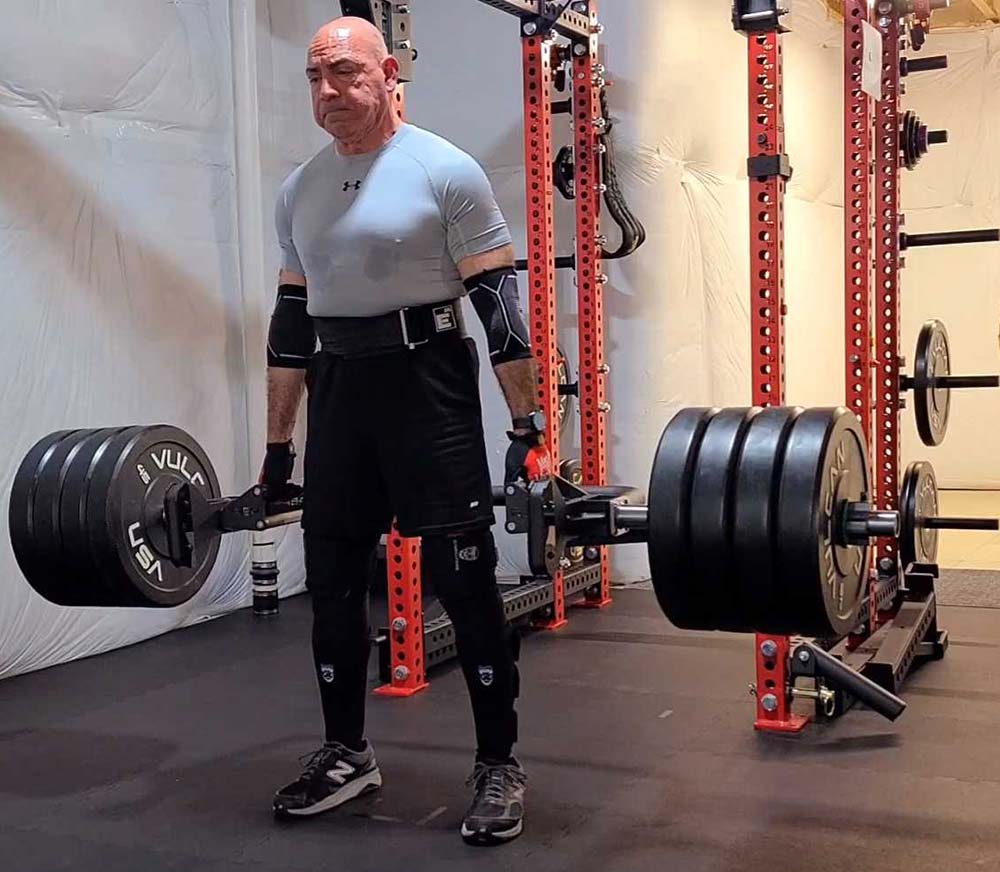 A picture of Ed Frank deadlifting 435 pounds in a home gym.